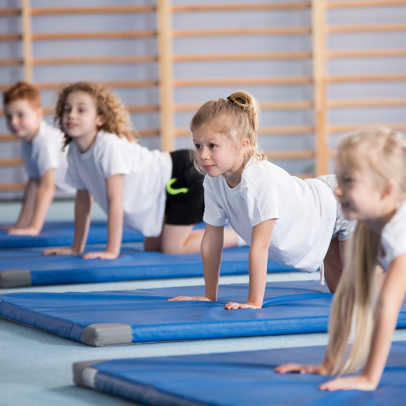 Happy girl exercising on blue mat during corrective gymnastics classes
